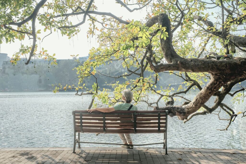 blogartikel 6 2 Eine Frau sitzt entspannt auf einer Bank an einem See.
