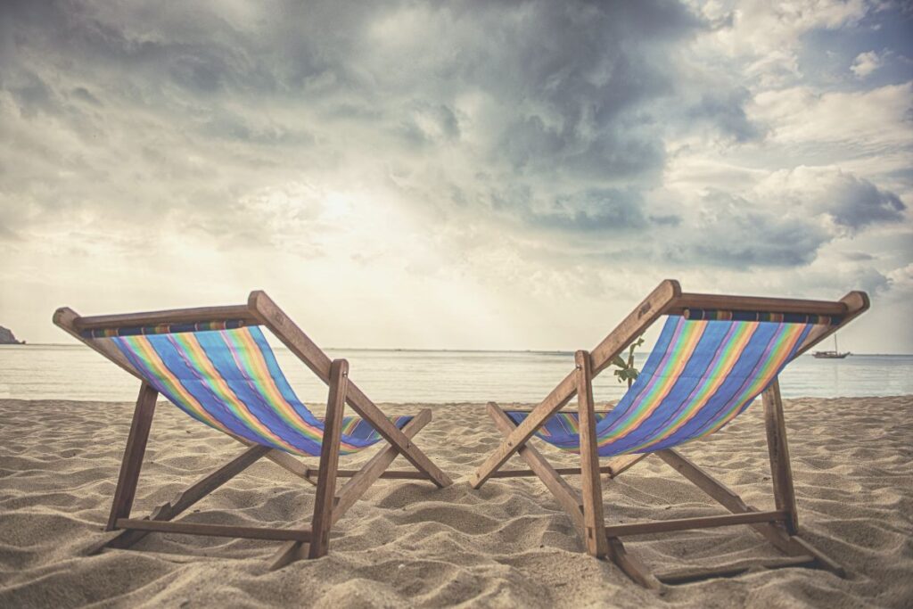 Zwei Liegestühle am Strand mit bewölktem Himmel als Symbol dafür warum Urlaub nicht automatisch innere Ruhe bringt.